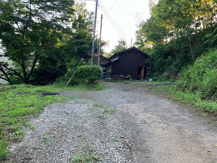 道なりにいちばん上まで進んでください。手前左手の砂利の辺りと、奥の茶色い小屋の手前に整頓して駐車してください